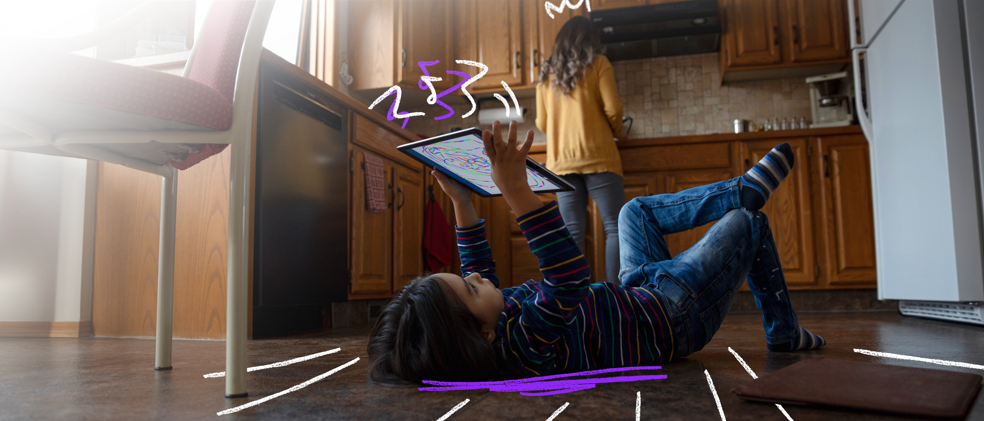A child plays with a device on the floor in the kitchen