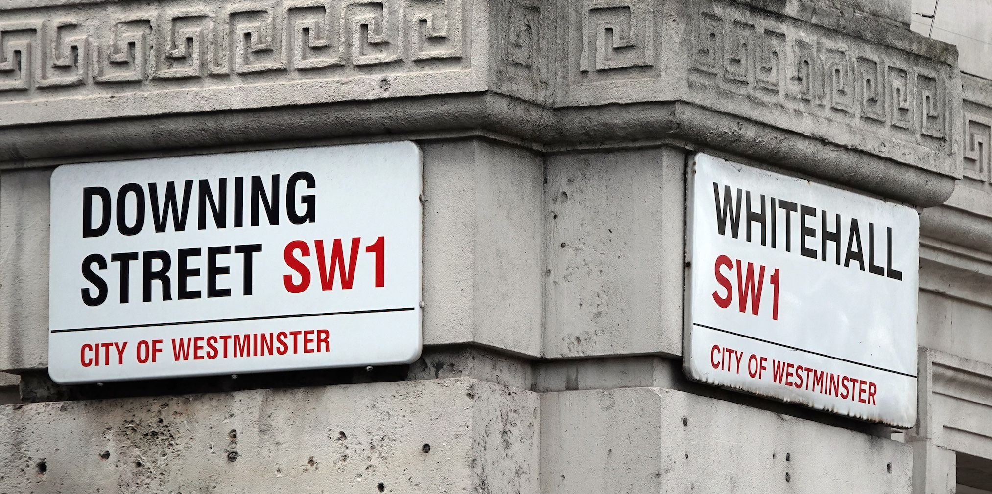 Downing Street and Whitehall street signs on the side of a building.